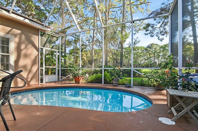 view of swimming pool with glass enclosure and a patio area