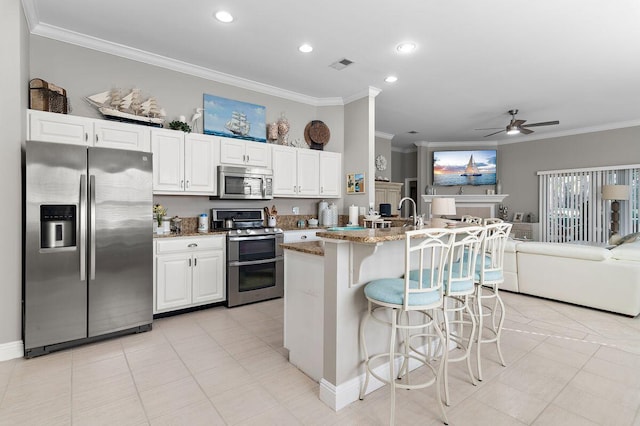 kitchen with ornamental molding, light stone countertops, stainless steel appliances, and white cabinets