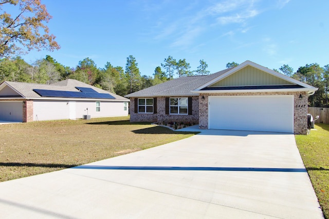 single story home featuring solar panels, a front yard, and a garage