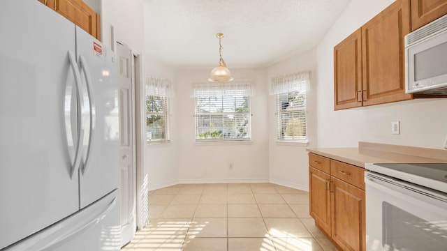 kitchen featuring white appliances, hanging light fixtures, light tile patterned floors, and a textured ceiling