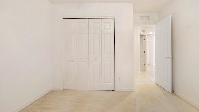 unfurnished bedroom featuring light carpet and a closet