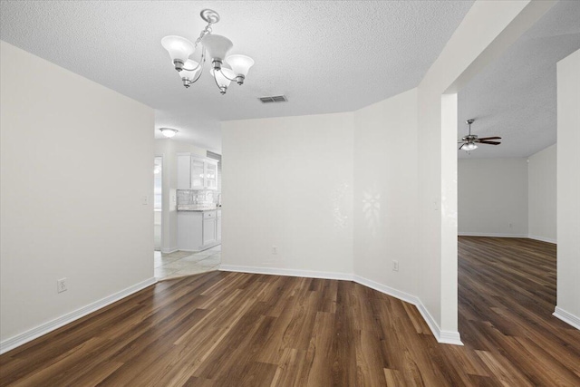 interior space featuring ceiling fan with notable chandelier, dark hardwood / wood-style flooring, and a textured ceiling