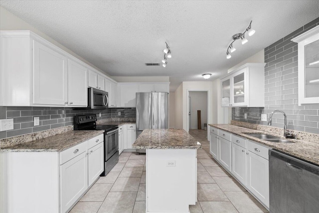 kitchen with a kitchen island, sink, stainless steel appliances, and white cabinets