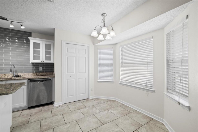 kitchen featuring stainless steel dishwasher, tasteful backsplash, sink, pendant lighting, and white cabinetry