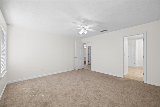 empty room featuring a textured ceiling, ceiling fan, and light colored carpet