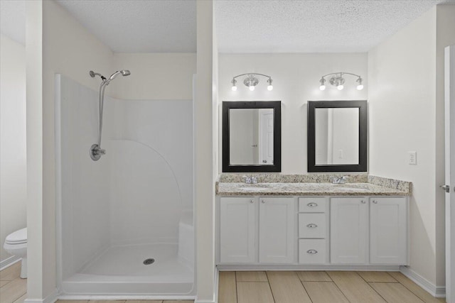 bathroom with vanity, toilet, a shower, and a textured ceiling