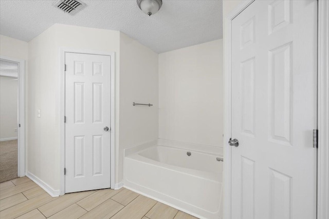 bathroom with a bath and a textured ceiling