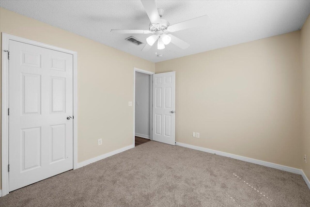 unfurnished bedroom featuring ceiling fan, carpet floors, and a textured ceiling