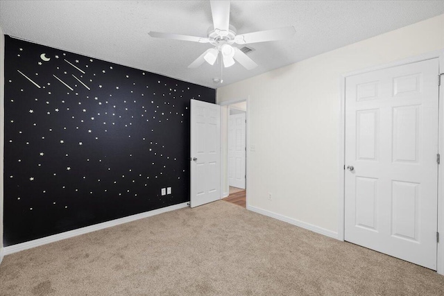 unfurnished bedroom with a textured ceiling, ceiling fan, and light colored carpet