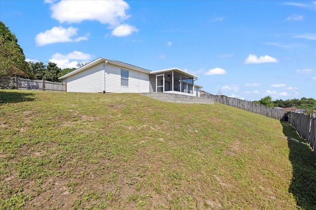 back of property featuring a sunroom and a lawn