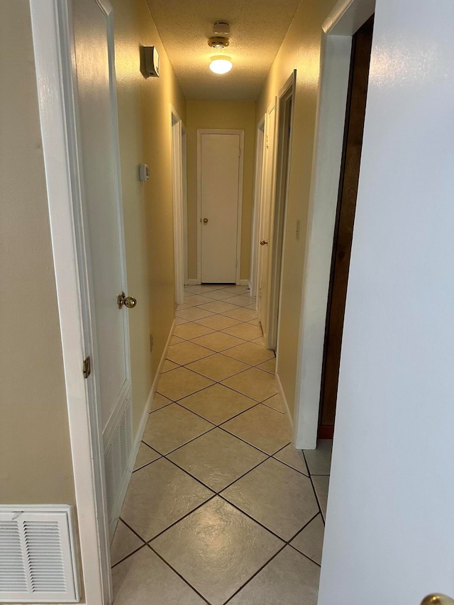 hall with light tile patterned floors and a textured ceiling