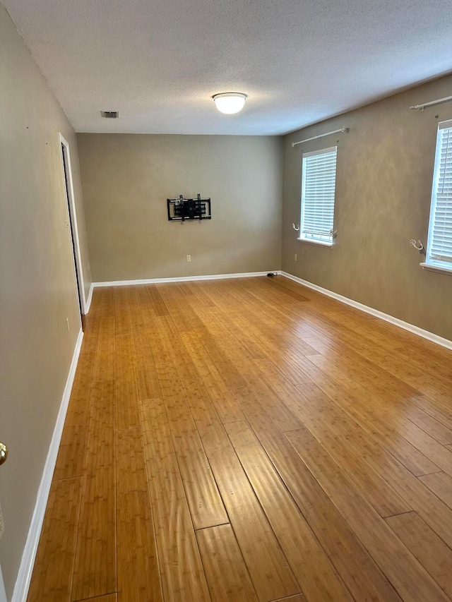 unfurnished room with light hardwood / wood-style flooring and a textured ceiling