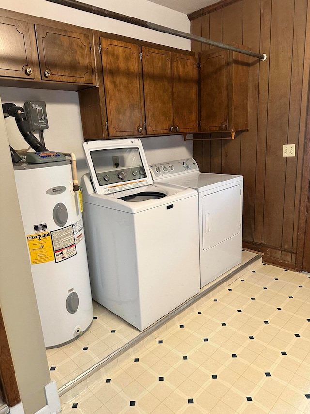 laundry area featuring wood walls, washing machine and clothes dryer, water heater, and cabinets