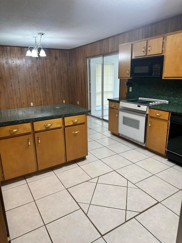 kitchen featuring wood walls, an inviting chandelier, decorative backsplash, black appliances, and light tile patterned floors