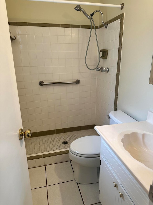 bathroom with a tile shower, tile patterned floors, vanity, and toilet