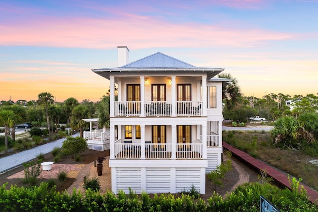 back house at dusk featuring a balcony