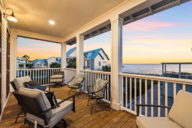 deck at dusk featuring a water view