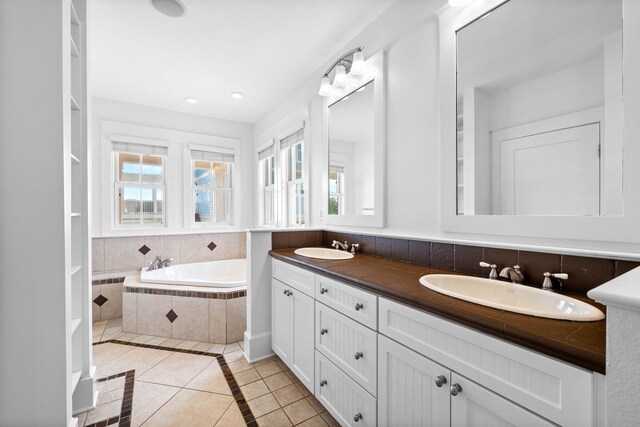 bathroom featuring a relaxing tiled tub, tile patterned flooring, and vanity