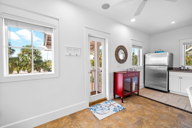 kitchen with ceiling fan, stainless steel refrigerator, white cabinets, and a healthy amount of sunlight