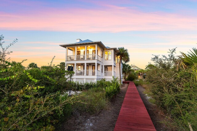 back house at dusk with a balcony