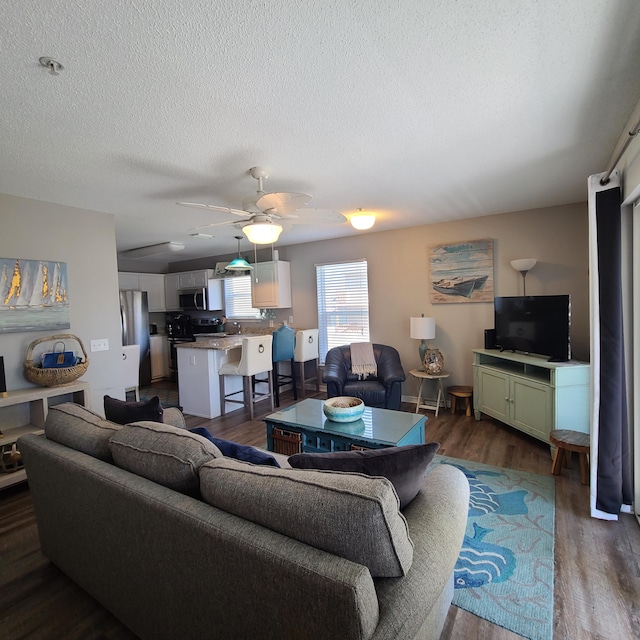 living room featuring sink, dark hardwood / wood-style flooring, a textured ceiling, and ceiling fan