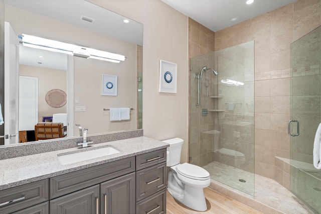 bathroom featuring vanity, hardwood / wood-style flooring, toilet, and an enclosed shower