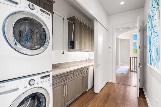 laundry area with cabinets, sink, dark hardwood / wood-style flooring, and stacked washer and dryer