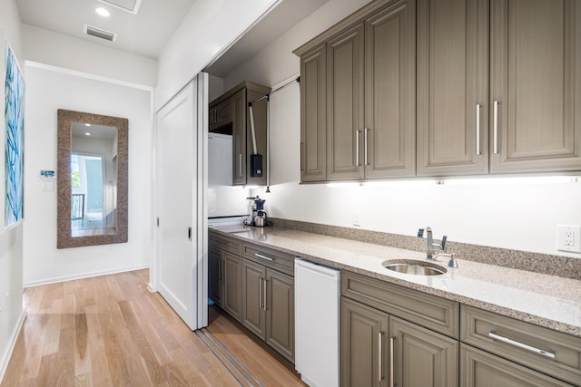 kitchen featuring light stone countertops, light hardwood / wood-style flooring, and sink