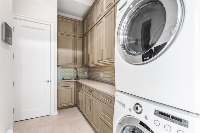 laundry area with light tile patterned flooring, cabinets, and stacked washer / drying machine