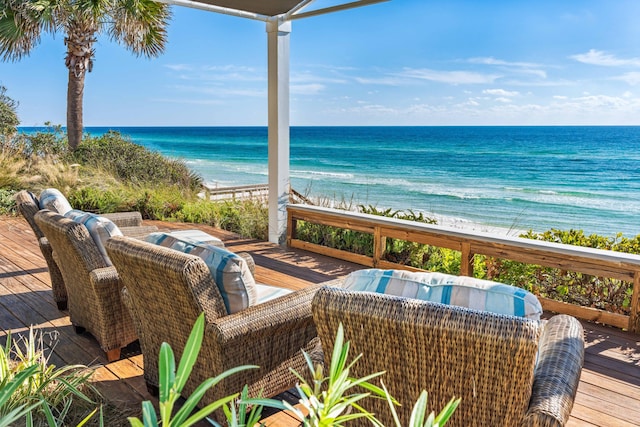 wooden terrace featuring a water view and a view of the beach