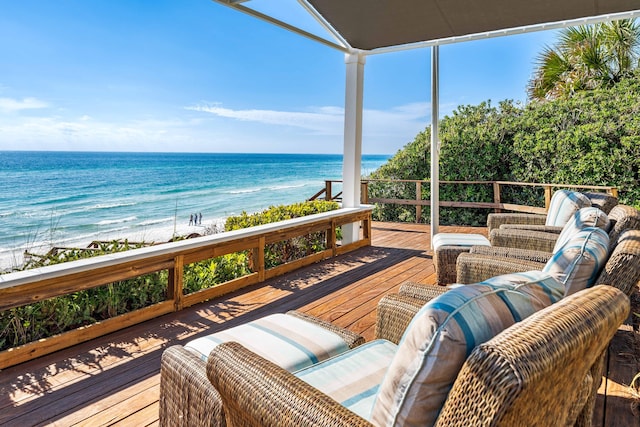 wooden terrace featuring a beach view and a water view