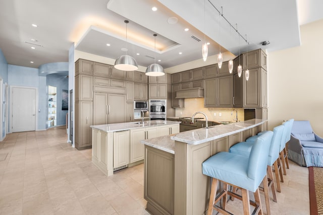 kitchen featuring a kitchen bar, hanging light fixtures, appliances with stainless steel finishes, light stone counters, and kitchen peninsula