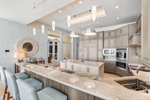 kitchen featuring light stone countertops, appliances with stainless steel finishes, sink, hanging light fixtures, and a breakfast bar area