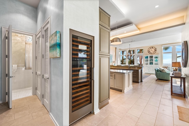 interior space with a raised ceiling, light tile patterned flooring, and beverage cooler