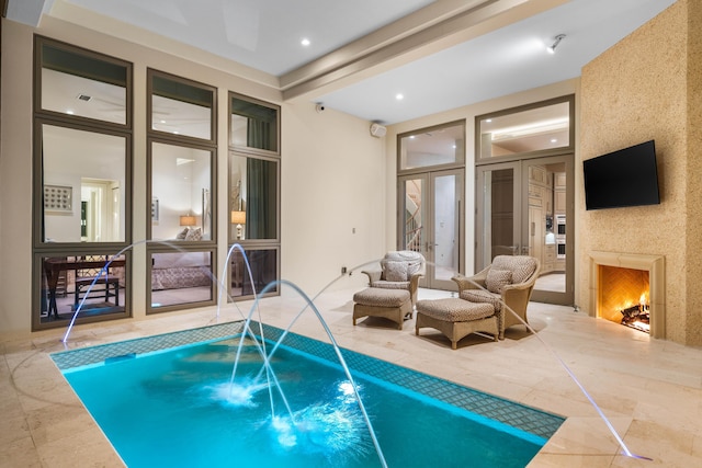 view of pool with a high end fireplace, a jacuzzi, french doors, and pool water feature