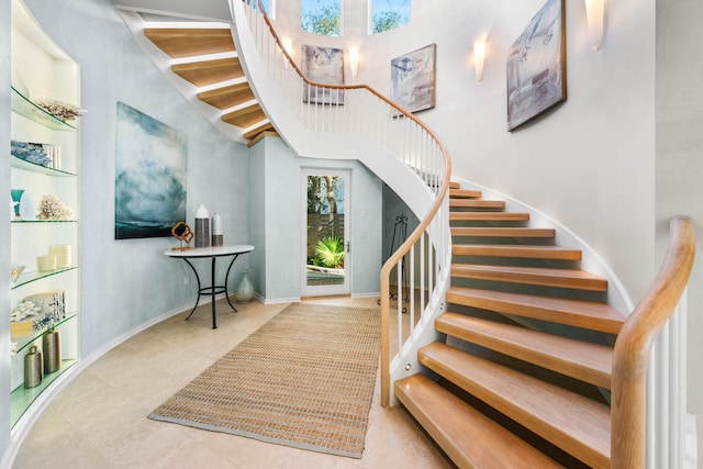 stairs with tile patterned flooring and a towering ceiling