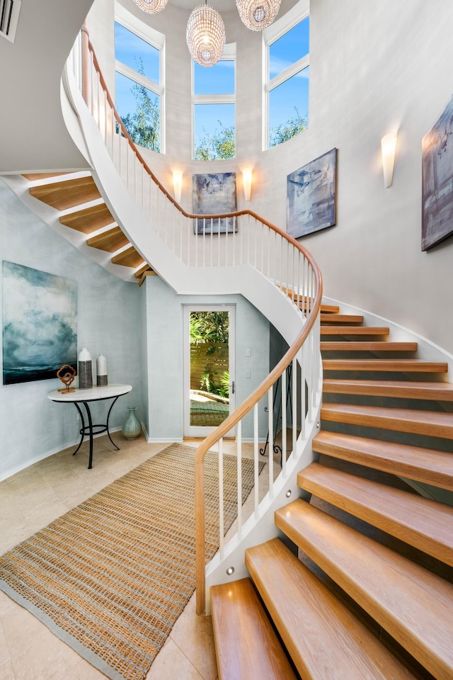 stairway with tile patterned flooring, a high ceiling, and a chandelier