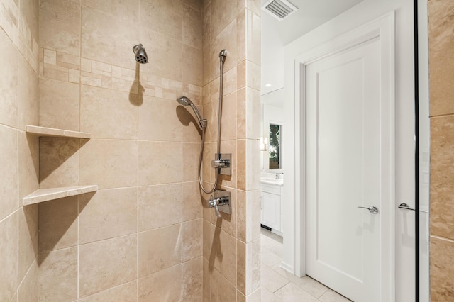 bathroom featuring a tile shower, tile patterned floors, and vanity