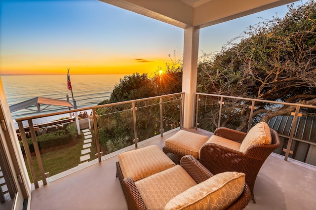 balcony at dusk featuring a water view