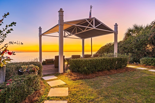 patio terrace at dusk with a yard and a water view