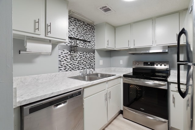 kitchen with white cabinets, stainless steel appliances, backsplash, and sink