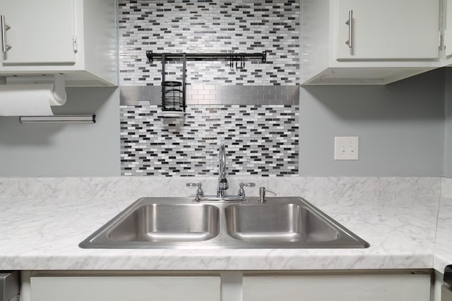 kitchen featuring backsplash, sink, and white cabinetry