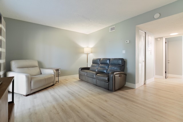 living room with light hardwood / wood-style floors and a textured ceiling