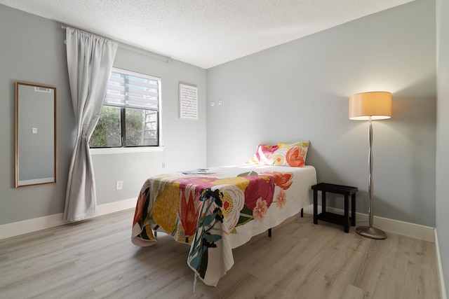 bedroom with light wood-type flooring and a textured ceiling