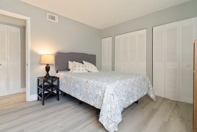 bedroom with hardwood / wood-style flooring and two closets