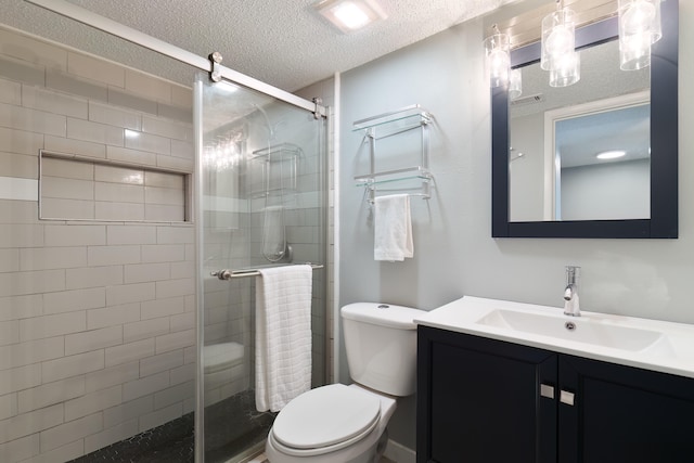 bathroom with vanity, toilet, a shower with shower door, and a textured ceiling