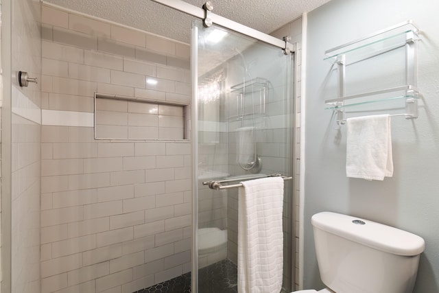 bathroom with toilet, a shower with shower door, and a textured ceiling