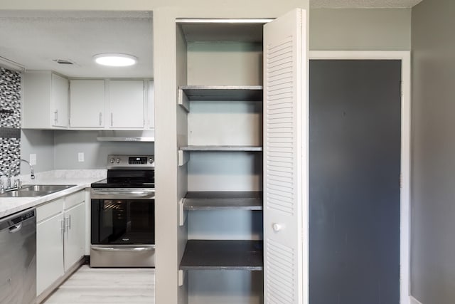 kitchen featuring light hardwood / wood-style floors, sink, stainless steel appliances, and white cabinets