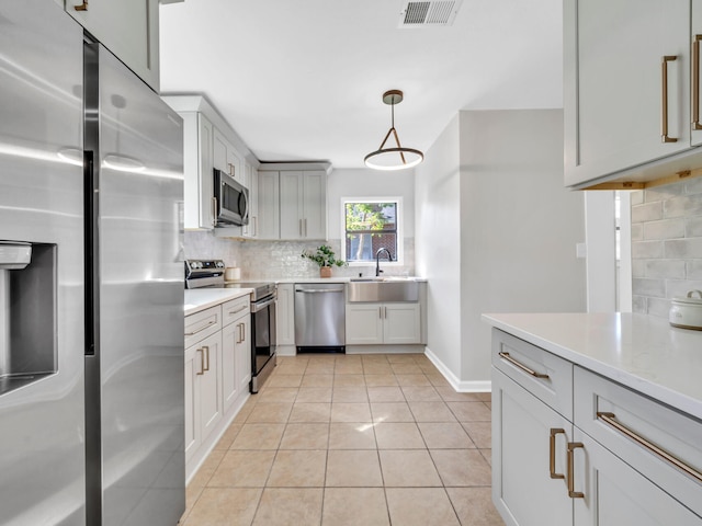 kitchen with tasteful backsplash, sink, appliances with stainless steel finishes, decorative light fixtures, and light tile patterned floors