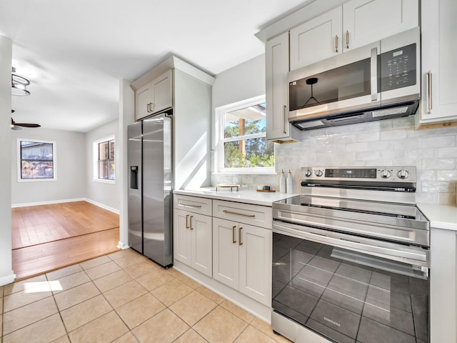 kitchen featuring decorative backsplash, appliances with stainless steel finishes, light hardwood / wood-style flooring, and ceiling fan